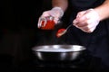 Adding red caviar for the sauce. Preparation of creamy caviar sauce for fish dishes. Photo on a black background. Unrecognizable