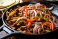 adding sliced onions into a simmering beef fajita