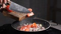 Adding sloced tomato into pan with frying onion, oil splashing. Cooking process. Tomatoes in hot pan are fried at home