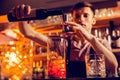 Dark-haired bartender adding some alcohol to the cocktail