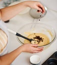 Adding some edible magic. a woman adding chocolate chips to her batter.