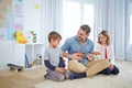 Adding some fun to their day. a happy father playing the guitar for his son and daughter at home. Royalty Free Stock Photo