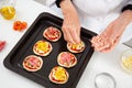 Adding toppings to the mini pizzas. Adding ham to the Hawaiian pizza. Delicious homemade mini pizzas preparation Royalty Free Stock Photo