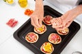 Adding toppings to the mini pizzas. Adding ham to the Hawaiian pizza. Delicious homemade mini pizzas preparation Royalty Free Stock Photo