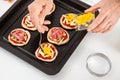 Adding toppings to the mini pizzas. Adding pineapple to the Hawaiian pizza. Delicious homemade mini pizzas preparation Royalty Free Stock Photo