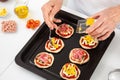 Adding toppings to the mini pizzas. Adding pineapple to the Hawaiian pizza. Delicious homemade mini pizzas preparation Royalty Free Stock Photo