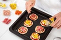 Adding toppings to the mini pizzas. Adding pineapple to the Hawaiian pizza. Delicious homemade mini pizzas preparation Royalty Free Stock Photo