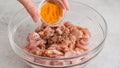 Adding turmeric to chopped chicken fillet . Glass bowl with the chopped marinated chicken meat close-up