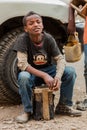 Young teenager working as a shoe shine boy on the street, looking straight at the camera