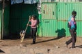 Young woman sweeping the front entrance to her informal store in