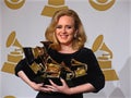 Adele holding trophys at the Grammy Awards