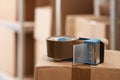 Adhesive tape dispenser on cardboard box indoors, closeup Royalty Free Stock Photo