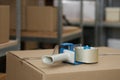 Adhesive tape dispenser on cardboard box indoors. Space for text Royalty Free Stock Photo