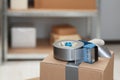 Adhesive tape dispenser on cardboard box indoors. Space for text Royalty Free Stock Photo