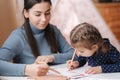Adirable little girl with her beautiful young mom draws in the album using color pensins. Cute girl paints coloring page Royalty Free Stock Photo