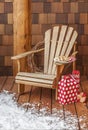 Adirondack chair with Christmas gifts on the snowy wooden porch deck of a rustic country cabin. Winter holiday vacation homes.