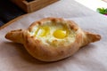 Adjara khachapuri - cheese pie with egg yolk and butter on paper