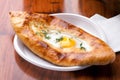 Adjarian khachapuri, fried eggs in flat cake close-up on table