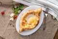 Adjarian Khachapuri traditional Georgian dish with sulguni cheese filled bread and egg yolk on tablecloth Royalty Free Stock Photo