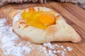 Adjarian khachapuri on the wooden floured cutting board close-up