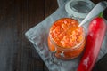 Adjika hot chili pepper sauce paste harissa in glass jar. Tunisia, georgian and arabic cuisine. Close up. Space for text