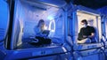 Adjoined rooms of a capsule hotel with a guy and a girl in them