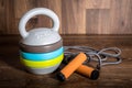 Adjustable kettlebell and jumping rope on wooden background. Weights for a fitness training.