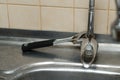 An adjustable spanner lies on a rusty kitchen faucet. Incomplete repair process