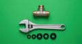 Plumbing Essentials: Adjustable Wrench, Brass Tee, and Rubber Seals on Green Background Royalty Free Stock Photo