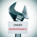 Adjustable wrench and signboard with the text under maintenance