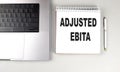 ADJUSTED EBITA text on notebook with laptop and pen Royalty Free Stock Photo