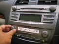 adjusting air-conditioning air-conditioning or heater knob beneath dusty car audio display.