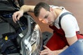 Adjusting the headlights on the car by mechanics in a garage