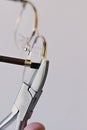 Adjusting inclination of temples on modern metal eyeglass frame with conical inclination pliers Royalty Free Stock Photo