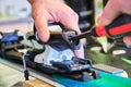 Adjusting a ski binding rear piece release tension spring, using a flathead screwdriver - close up of ski service worker hand