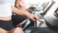 Adjusting speed. Woman exercising on treadmill, training in gym