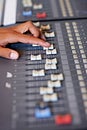 Adjusting the volume on a mix. Cropped close-up image of a hand moving a slider on a mixing desk.