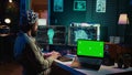 IT admin coding and using EEG headset to upload brain into green screen laptop