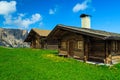 Cute wooden houses on the alpine green fields, Dolomites, Italy