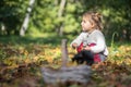 adoarle toddler girl sits and plays in the grass and autumn yellow leaves. in the foreground in blur is a basket with Royalty Free Stock Photo