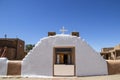 Adobe mud pueblo mission church with gate to plaza courtyard painted white and mission entrance door showing through with other