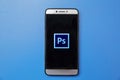 Adobe Photoshop logo on smartphone screen on blue background. Man holding smartphone with Adobe photoshop logo on the screen. Royalty Free Stock Photo
