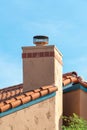 Adobe style chimney on a ranch style home or house with cream or beige cement exterior and visible metal vents in yard Royalty Free Stock Photo