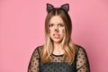 Adolescent in black dress, headband like cat ears, face painting. She posing on pink background. Close up Royalty Free Stock Photo