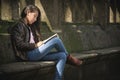 Teenage girl sitting on a park bench reading a book