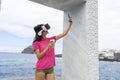 Adolescent taking selfie with virtual reality glasses with her cellphone while taking a take away coffee in the sea, to sharing in