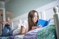 Adolescent teen girl reading a book while lying in bed at home in her bedroom. Lifestyle and learning photo Royalty Free Stock Photo