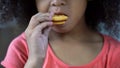 Adorable African-American girl biting sweet cookie, unhealthy nutrition close-up Royalty Free Stock Photo