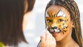 Adorable african-american girl getting tiger face painting Royalty Free Stock Photo