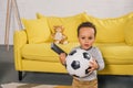 adorable african american toddler holding soccer ball and remote controller